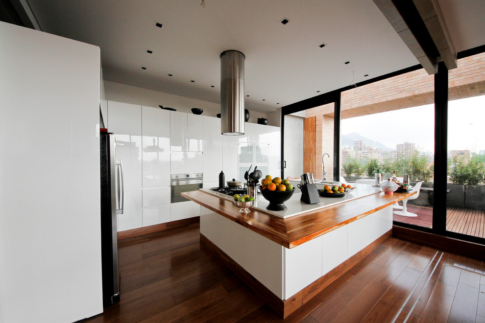 Moderne Küche mit Doppelwaschbecken, flächenbündigen Schrankfronten, weißen Schränken, Arbeitsplatte aus Holz und weißen Elektrogeräten in Sonstige