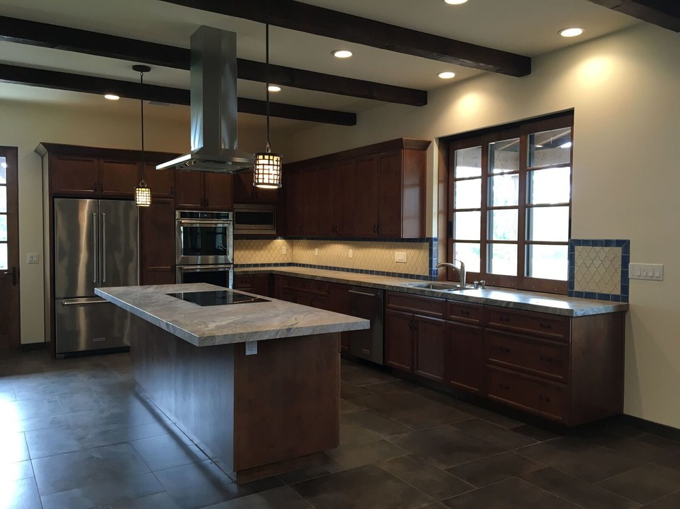 Photo of a medium sized l-shaped open plan kitchen in San Diego with a double-bowl sink, recessed-panel cabinets, dark wood cabinets, marble worktops, white splashback, cement tile splashback, stainless steel appliances, slate flooring, an island and grey floors.