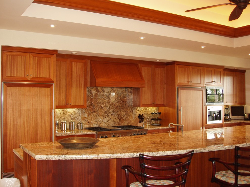 Bild på ett funkis kök, med en undermonterad diskho, skåp i shakerstil, skåp i mellenmörkt trä, granitbänkskiva, grönt stänkskydd, stänkskydd i sten, rostfria vitvaror och en köksö