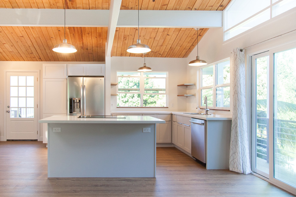 Photo of a medium sized urban l-shaped kitchen/diner in Hawaii with a submerged sink, shaker cabinets, grey cabinets, engineered stone countertops, white splashback, stainless steel appliances, medium hardwood flooring and an island.