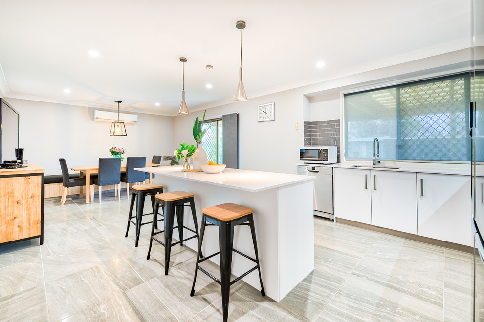 Moderne Wohnküche in L-Form mit Unterbauwaschbecken, flächenbündigen Schrankfronten, weißen Schränken, Küchenrückwand in Grau, Rückwand-Fenster, Küchengeräten aus Edelstahl, Kücheninsel und grauem Boden in Brisbane