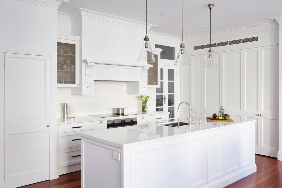 Design ideas for a large classic u-shaped kitchen in Sydney with white cabinets, white splashback, an island, a double-bowl sink, recessed-panel cabinets, ceramic splashback, stainless steel appliances and medium hardwood flooring.