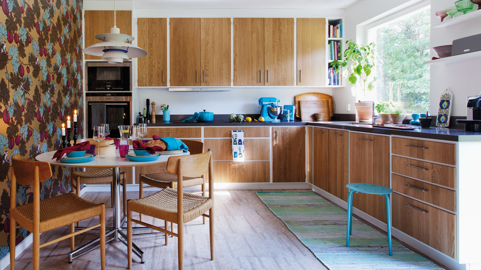Retro Wohnküche ohne Insel in L-Form mit flächenbündigen Schrankfronten, hellbraunen Holzschränken, Küchengeräten aus Edelstahl, Granit-Arbeitsplatte und Tapete in Göteborg