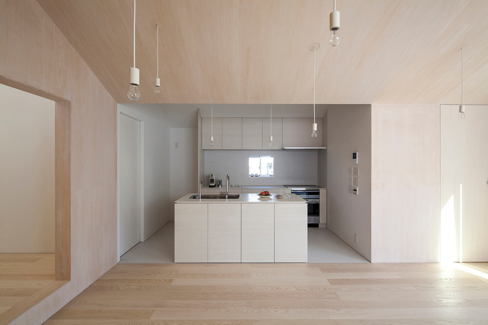 This is an example of a small modern galley open plan kitchen in Other with a submerged sink, light wood cabinets, composite countertops, white splashback, porcelain splashback, stainless steel appliances, porcelain flooring, an island, white floors and white worktops.