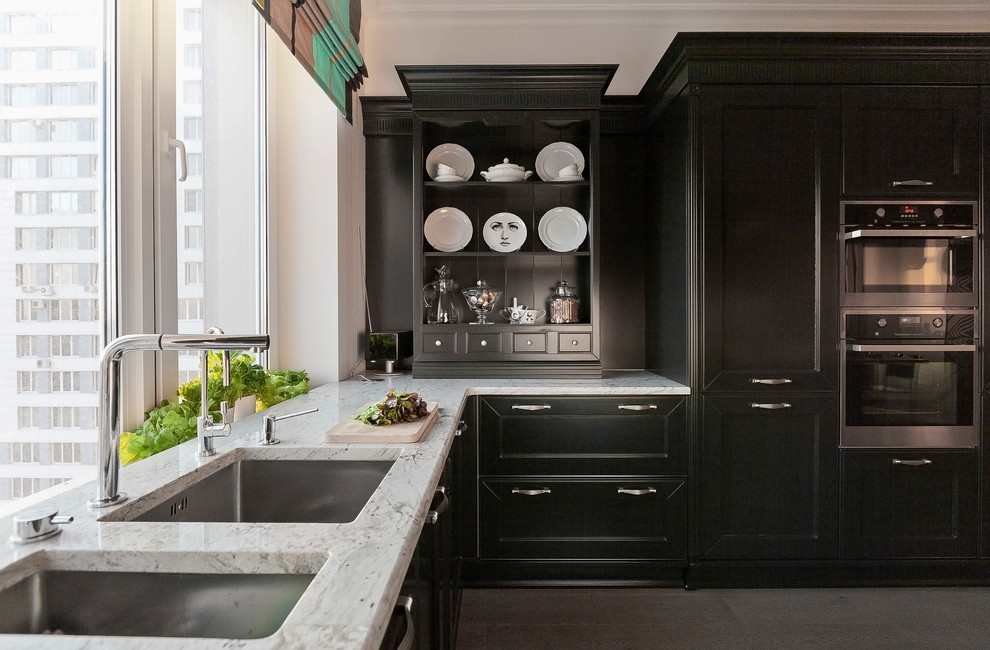 Cette photo montre une cuisine tendance en U avec un évier encastré, un placard avec porte à panneau encastré, des portes de placard noires et un électroménager noir.