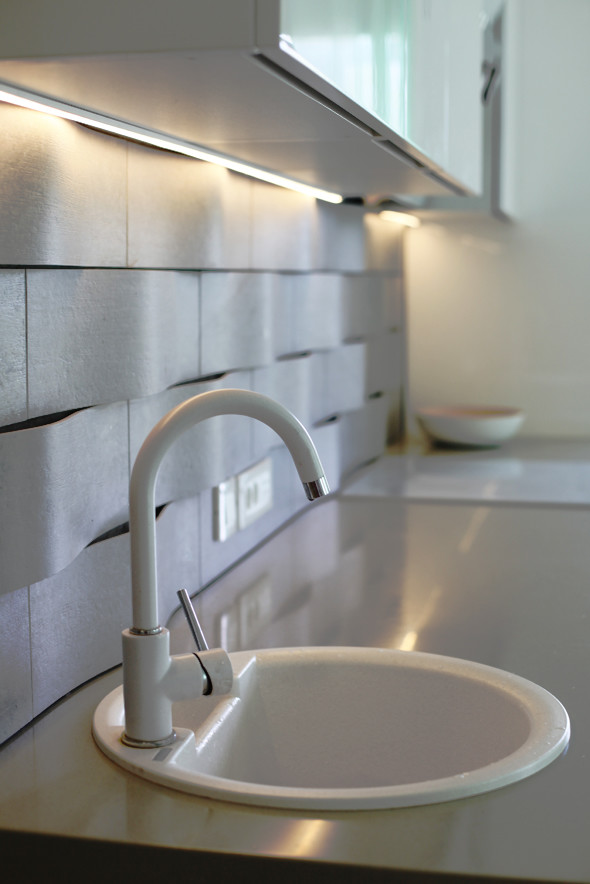 Esempio di una piccola cucina minimal con lavello a vasca singola, ante bianche, paraspruzzi bianco e pavimento in legno massello medio