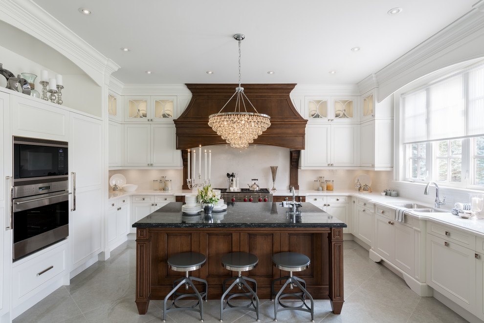 Klassische Küche in U-Form mit Doppelwaschbecken, Schrankfronten mit vertiefter Füllung, weißen Schränken, Küchenrückwand in Weiß, Küchengeräten aus Edelstahl und Kücheninsel in Toronto