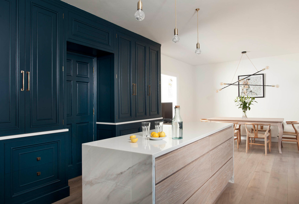 Große Moderne Wohnküche in L-Form mit flächenbündigen Schrankfronten, Schränken im Used-Look, Marmor-Arbeitsplatte, hellem Holzboden und Kücheninsel in Dublin