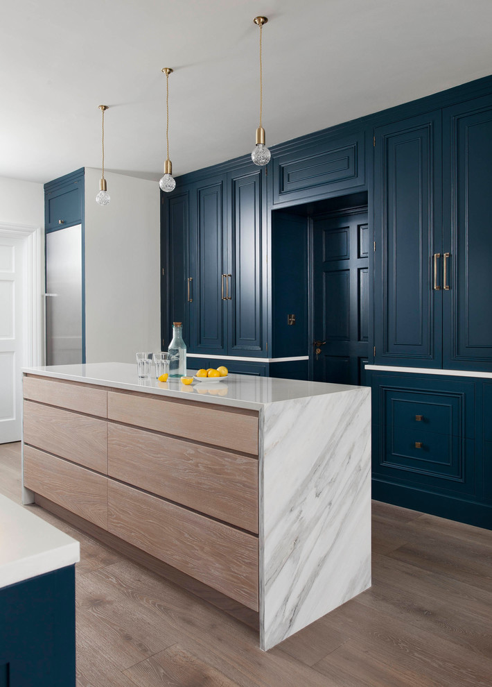 Foto de cocina clásica renovada con armarios con paneles empotrados, puertas de armario azules, electrodomésticos de acero inoxidable, suelo de madera en tonos medios y una isla
