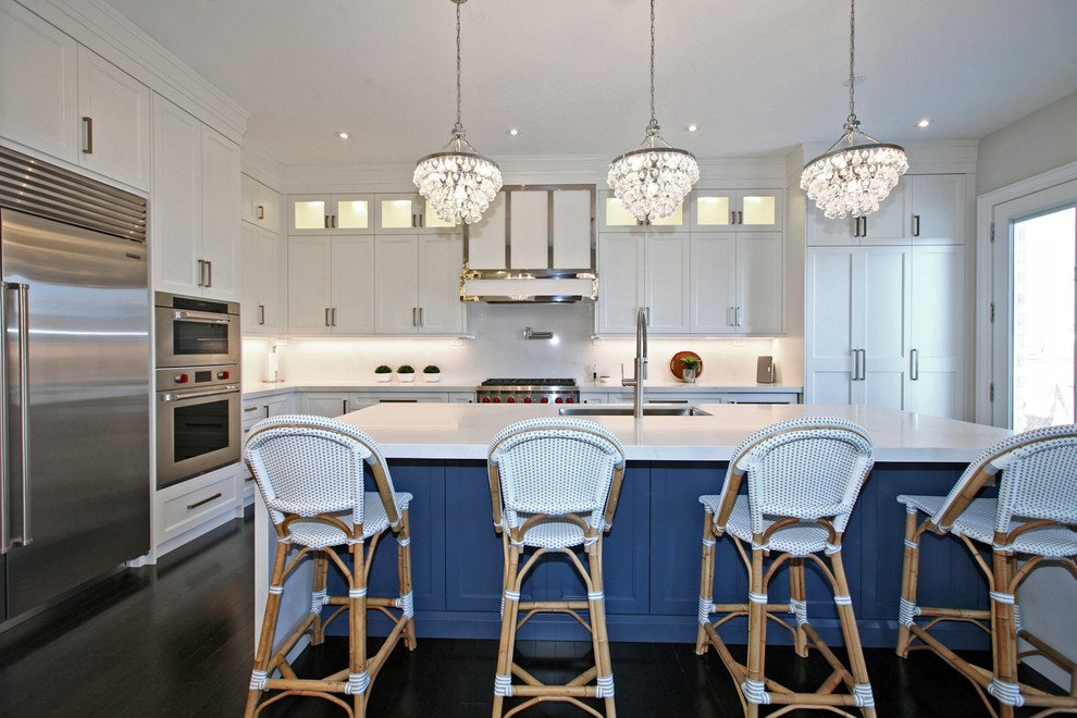 Photo of a large nautical l-shaped enclosed kitchen in Toronto with a submerged sink, shaker cabinets, white cabinets, marble worktops, stainless steel appliances, dark hardwood flooring, an island, brown floors and white worktops.