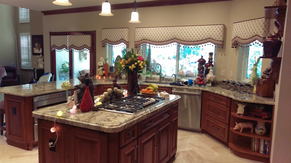 Photo of a large mediterranean u-shaped kitchen pantry in Phoenix with a submerged sink, raised-panel cabinets, brown cabinets, granite worktops, stainless steel appliances, marble flooring, an island and beige floors.