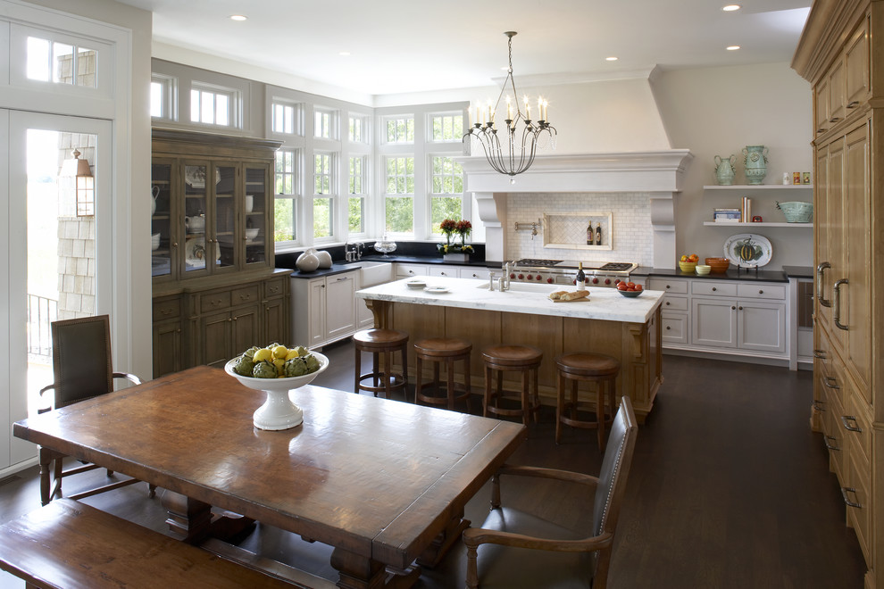 Foto de cocina comedor clásica con armarios con paneles con relieve, puertas de armario de madera oscura, salpicadero blanco y electrodomésticos de acero inoxidable