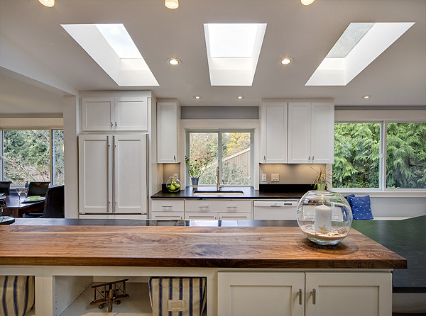 Inspiration for a mid-sized contemporary galley medium tone wood floor eat-in kitchen remodel in Seattle with an undermount sink, shaker cabinets, white cabinets, granite countertops, black backsplash, stone slab backsplash, white appliances and a peninsula