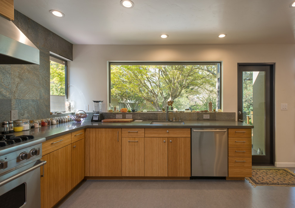 Bild på ett mellanstort funkis kök, med en undermonterad diskho, släta luckor, skåp i mellenmörkt trä, grått stänkskydd, stänkskydd i skiffer, rostfria vitvaror och grått golv