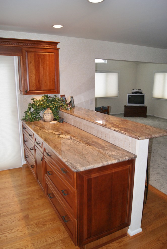 Eat-in kitchen - traditional l-shaped eat-in kitchen idea in Other with an undermount sink, recessed-panel cabinets, medium tone wood cabinets, granite countertops, beige backsplash, ceramic backsplash and white appliances