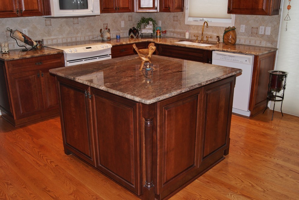 Example of a classic l-shaped eat-in kitchen design in Other with an undermount sink, recessed-panel cabinets, medium tone wood cabinets, granite countertops, beige backsplash, ceramic backsplash and white appliances