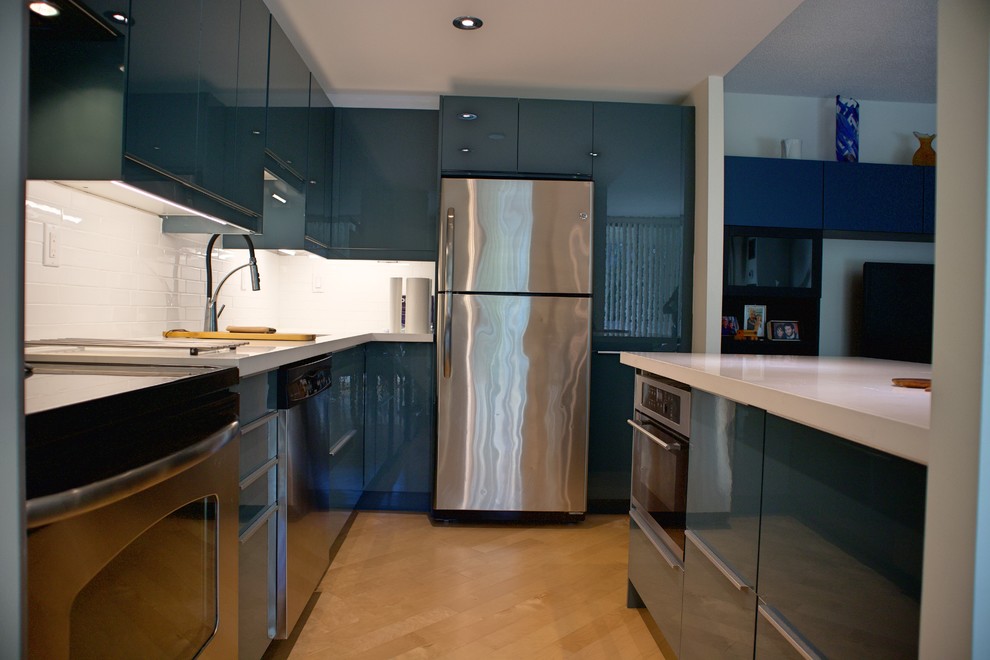 Foto på ett avskilt, mellanstort vit l-kök, med en enkel diskho, släta luckor, gröna skåp, bänkskiva i kvarts, vitt stänkskydd, stänkskydd i tunnelbanekakel, rostfria vitvaror, ljust trägolv, en halv köksö och gult golv