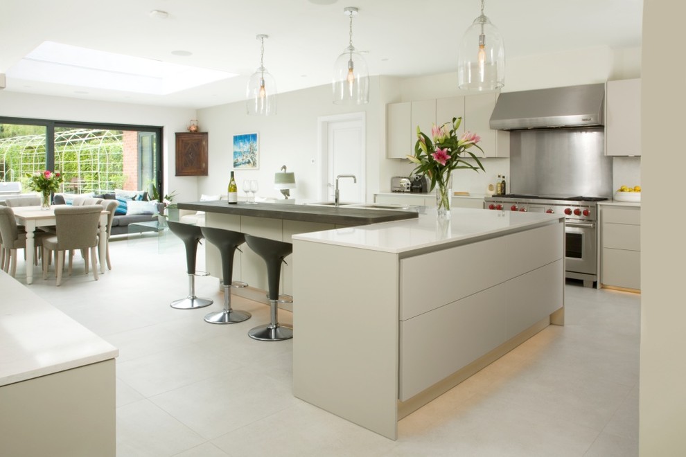 Photo of a large contemporary u-shaped kitchen/diner in Hertfordshire with a double-bowl sink, flat-panel cabinets, grey cabinets, quartz worktops, white splashback, stone slab splashback, stainless steel appliances, ceramic flooring, an island, white floors and white worktops.