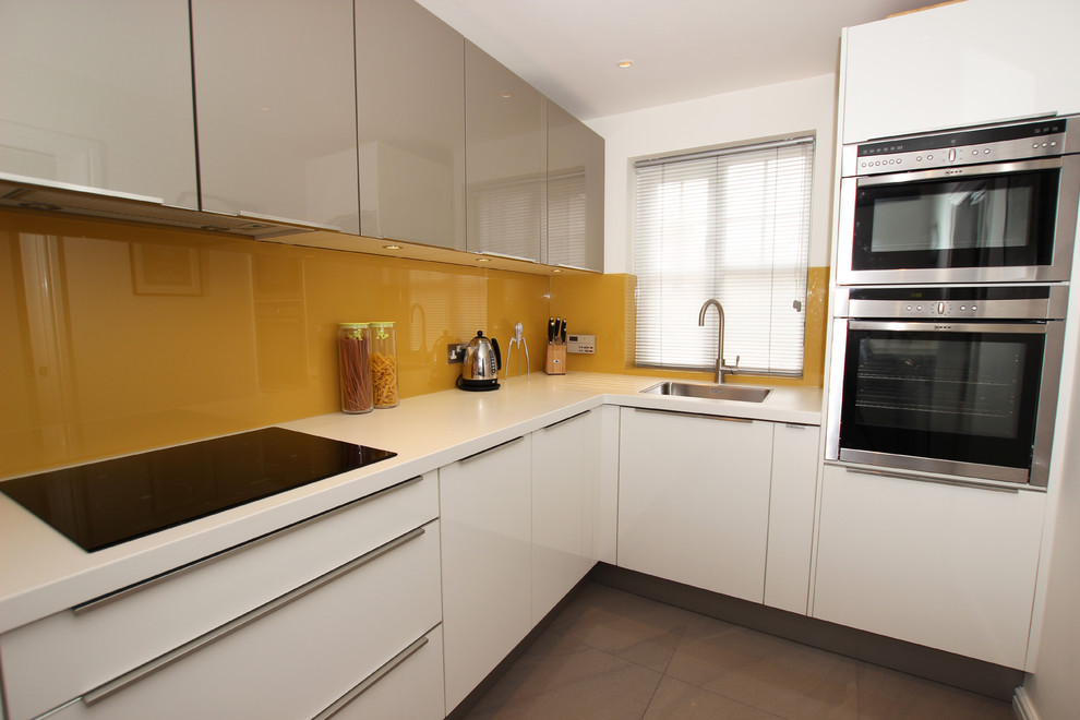 Cette image montre une cuisine minimaliste en L de taille moyenne avec des portes de placard blanches et un électroménager blanc.