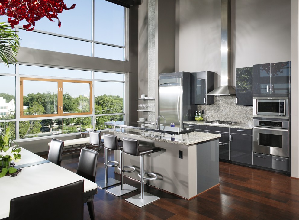 Inspiration for a contemporary galley kitchen/diner in Sacramento with stainless steel appliances, flat-panel cabinets, grey cabinets, grey splashback, granite worktops, stone slab splashback, dark hardwood flooring and brown floors.