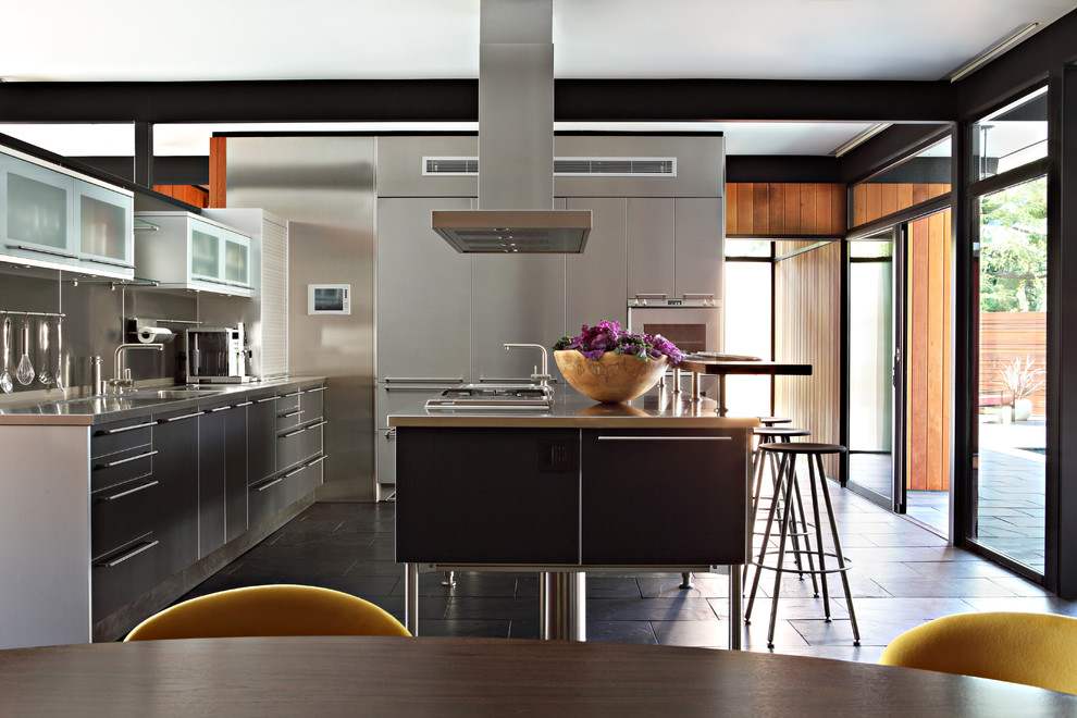 Inspiration for a contemporary l-shaped kitchen/diner in Los Angeles with an integrated sink, flat-panel cabinets, grey cabinets, stainless steel worktops, grey splashback and an island.