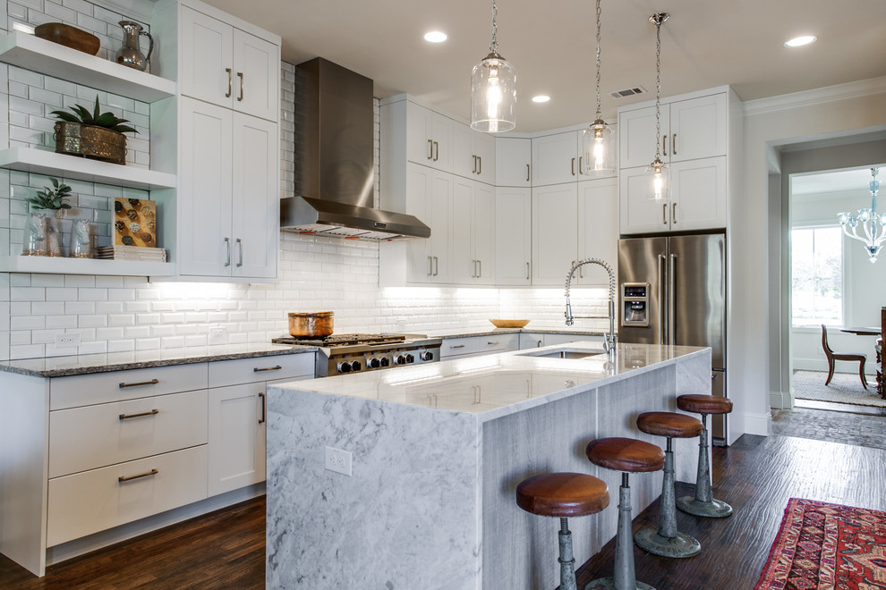 Photo of a farmhouse l-shaped kitchen in Dallas with a submerged sink, shaker cabinets, white cabinets, white splashback, stainless steel appliances, dark hardwood flooring and an island.