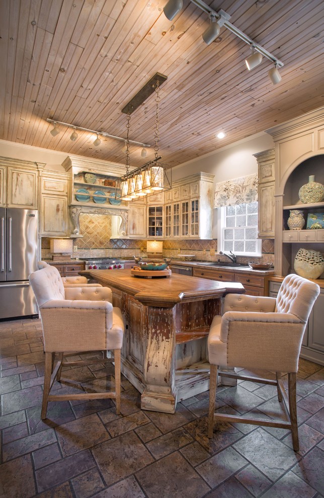 Large eclectic l-shaped porcelain tile and gray floor enclosed kitchen photo in Charlotte with a drop-in sink, raised-panel cabinets, wood countertops, brown backsplash, ceramic backsplash, stainless steel appliances, an island and distressed cabinets
