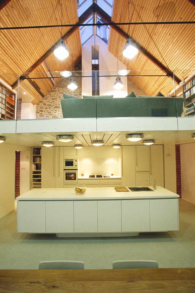 Bild på ett funkis kök, med en nedsänkt diskho, släta luckor, vita skåp, vitt stänkskydd och en köksö