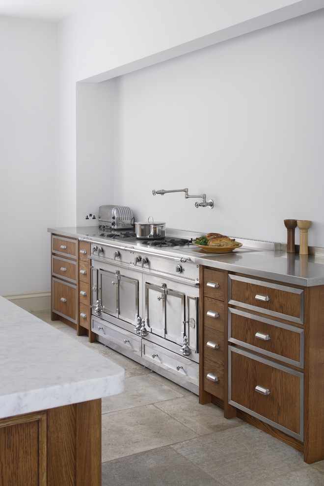 Example of a large galley limestone floor open concept kitchen design in Gloucestershire with a double-bowl sink, recessed-panel cabinets, dark wood cabinets, marble countertops and two islands