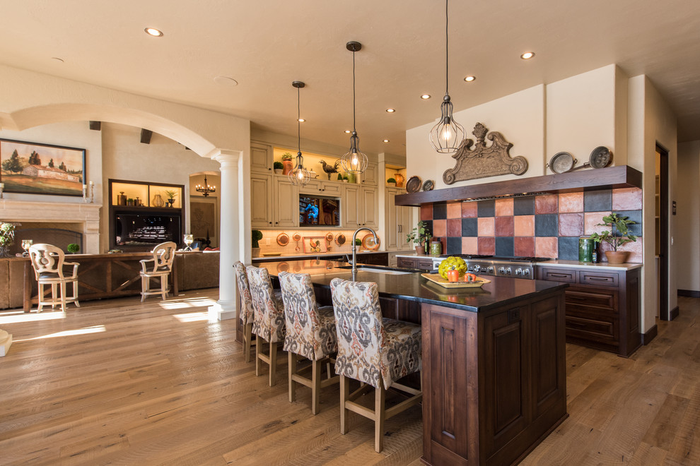 Mediterrane Küche mit Unterbauwaschbecken, profilierten Schrankfronten, bunter Rückwand, Küchengeräten aus Edelstahl, braunem Holzboden und Kücheninsel in Portland