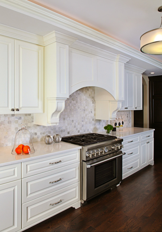 Example of a mid-sized classic l-shaped dark wood floor enclosed kitchen design in Detroit with an undermount sink, raised-panel cabinets, white cabinets, quartz countertops, metallic backsplash, stone tile backsplash, stainless steel appliances and an island