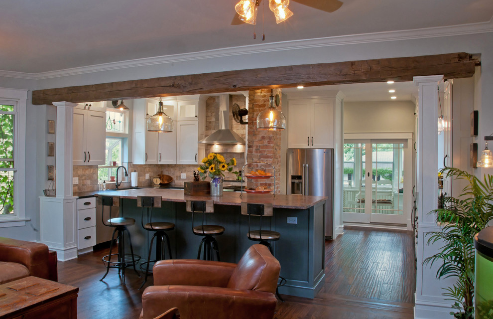Example of a mid-sized country l-shaped medium tone wood floor and brown floor eat-in kitchen design in Chicago with shaker cabinets, white cabinets, stainless steel appliances, an island, a farmhouse sink, soapstone countertops, stone tile backsplash and brown backsplash