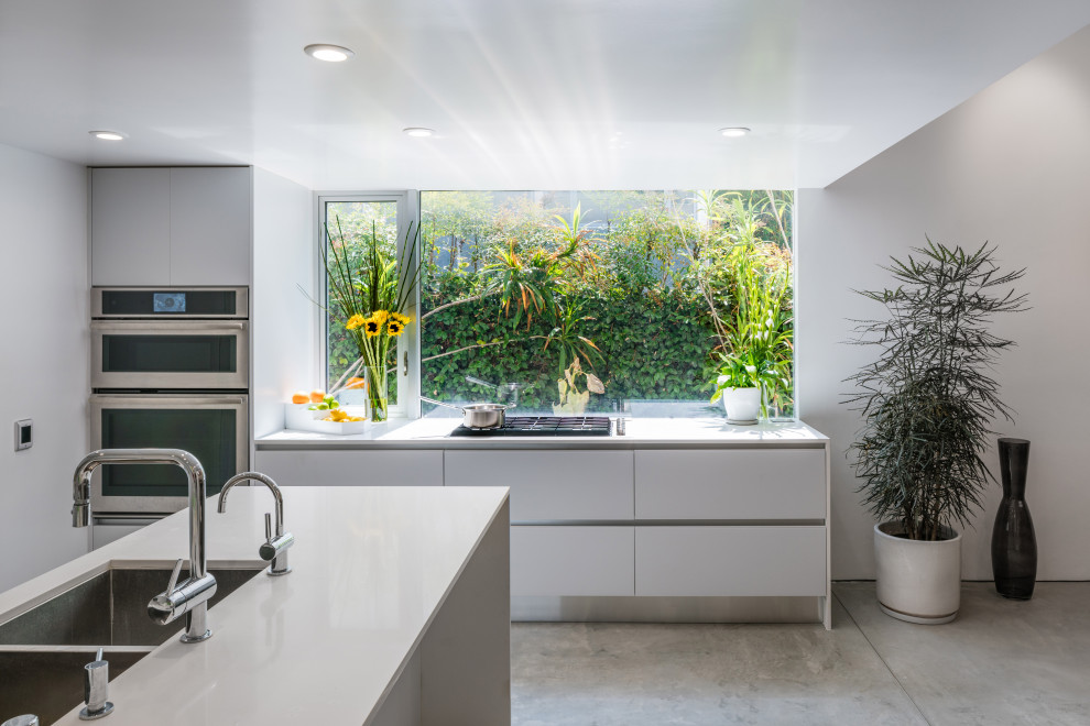 Cette photo montre une cuisine moderne de taille moyenne avec un placard à porte plane, des portes de placard grises, un plan de travail en quartz et îlot.