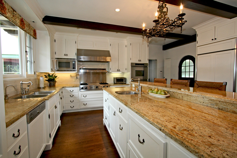 Пример оригинального дизайна: угловая кухня в классическом стиле с двойной мойкой, фасадами в стиле шейкер, белыми фасадами, белым фартуком, фартуком из плитки кабанчик и техникой под мебельный фасад
