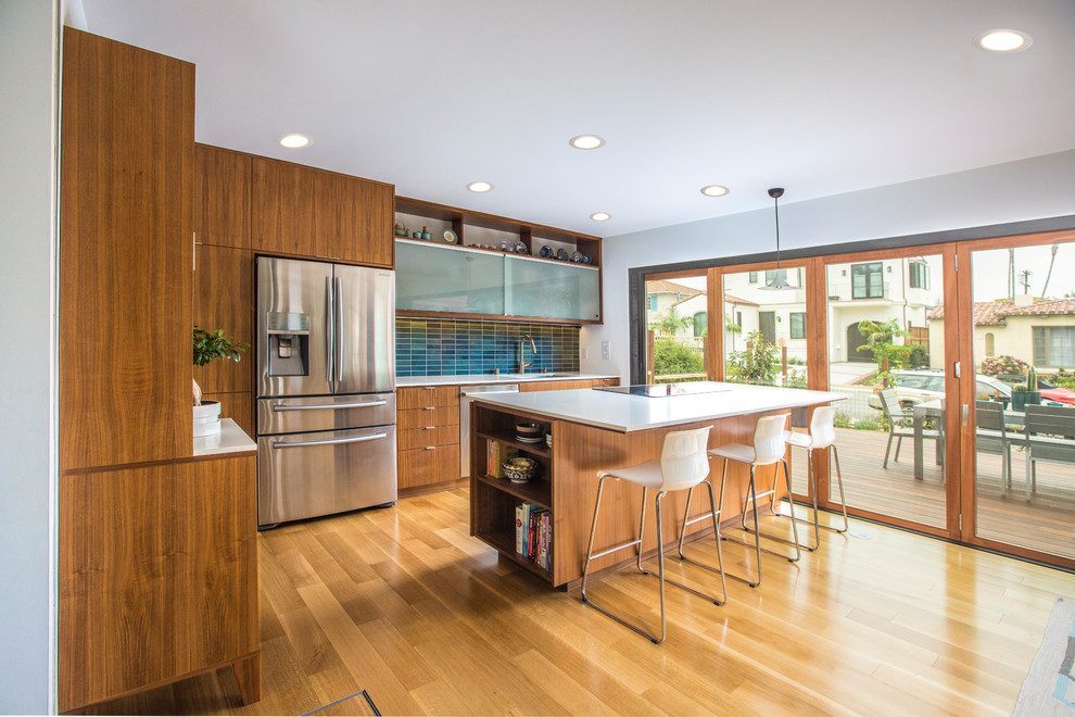 サンディエゴにあるミッドセンチュリースタイルのおしゃれなキッチン (フラットパネル扉のキャビネット、中間色木目調キャビネット、青いキッチンパネル、シルバーの調理設備、無垢フローリング、茶色い床) の写真