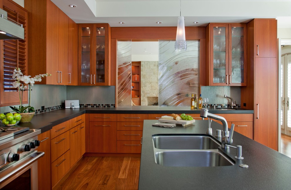 Idée de décoration pour une cuisine design en U et bois brun avec un évier 2 bacs, un placard à porte plane, une crédence multicolore, un plan de travail en granite, un sol en bois brun et îlot.