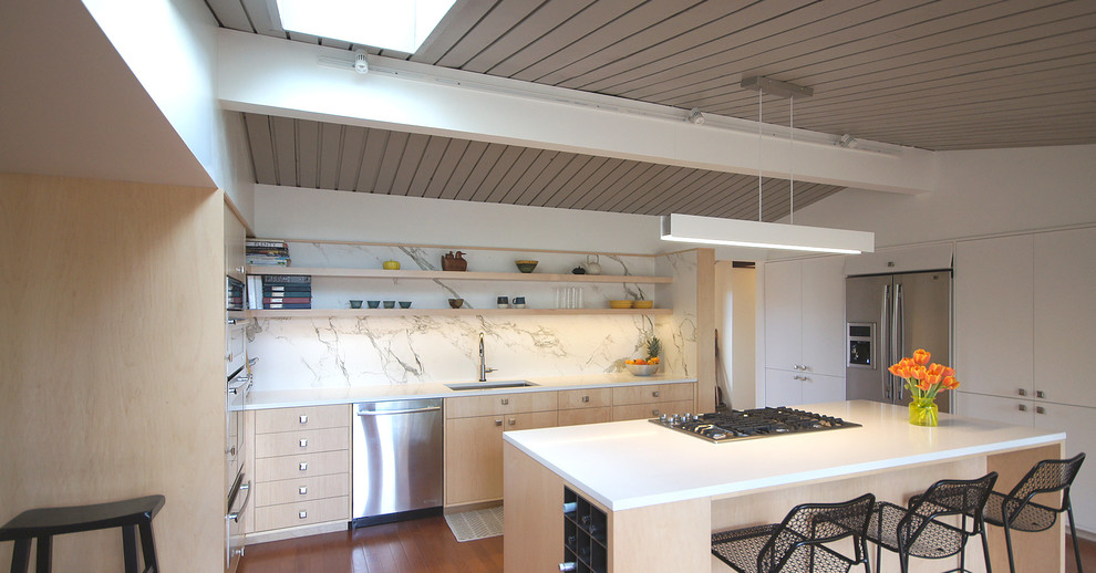 Foto på ett mellanstort funkis kök, med en undermonterad diskho, släta luckor, skåp i ljust trä, bänkskiva i koppar, vitt stänkskydd, rostfria vitvaror, mellanmörkt trägolv, en köksö, stänkskydd i marmor och brunt golv
