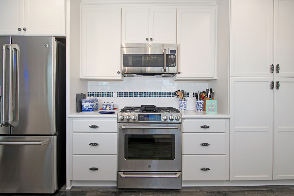 Eat-in kitchen - large coastal u-shaped medium tone wood floor and brown floor eat-in kitchen idea in San Diego with a drop-in sink, recessed-panel cabinets, white cabinets, granite countertops, white backsplash, subway tile backsplash, stainless steel appliances and a peninsula