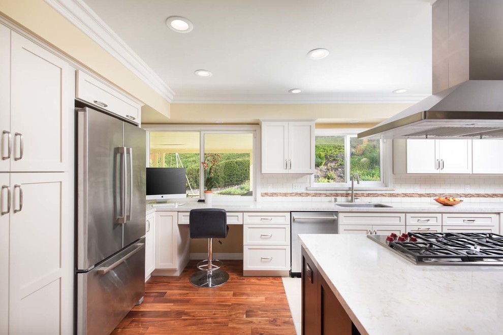 Inspiration for a huge timeless u-shaped medium tone wood floor eat-in kitchen remodel in San Diego with a drop-in sink, recessed-panel cabinets, white cabinets, quartzite countertops, white backsplash, subway tile backsplash, stainless steel appliances and an island