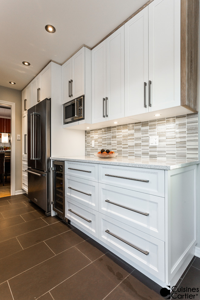 Example of a small danish galley ceramic tile enclosed kitchen design in Montreal with an undermount sink, shaker cabinets, white cabinets, gray backsplash, glass tile backsplash, stainless steel appliances and no island