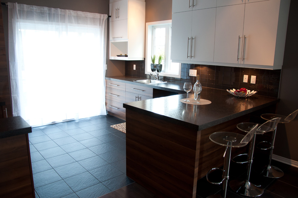 Trendy l-shaped ceramic tile kitchen photo in Montreal with a drop-in sink, flat-panel cabinets, medium tone wood cabinets, laminate countertops, black backsplash, ceramic backsplash and a peninsula