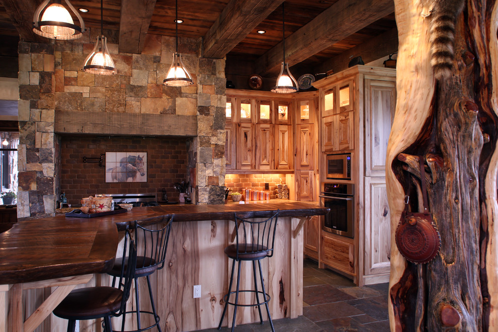 Inredning av ett rustikt stort kök, med luckor med infälld panel, skåp i ljust trä, träbänkskiva, rött stänkskydd, rostfria vitvaror, skiffergolv, stänkskydd i sten och en köksö