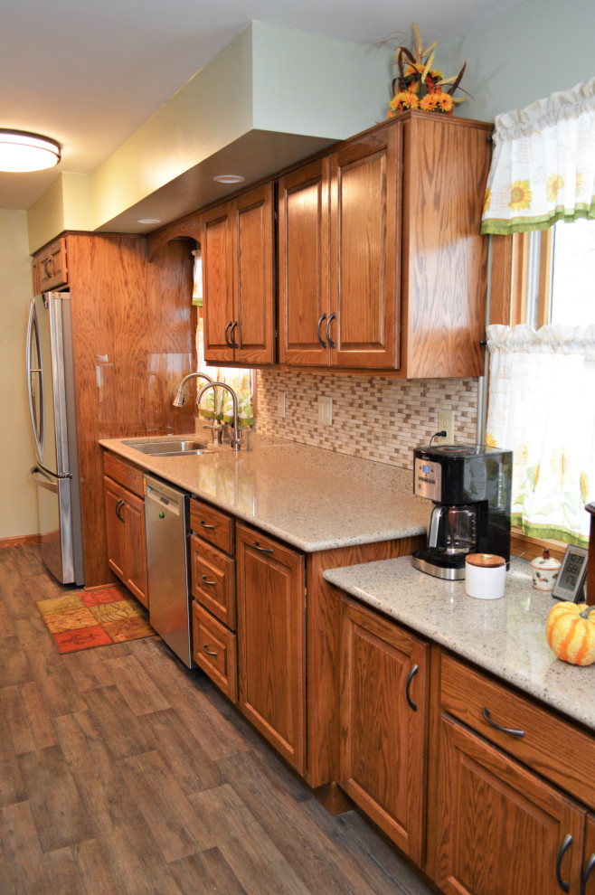 Medium sized rustic galley kitchen/diner in Chicago with a submerged sink, raised-panel cabinets, medium wood cabinets, quartz worktops, multi-coloured splashback, stainless steel appliances, laminate floors, no island, brown floors and beige worktops.