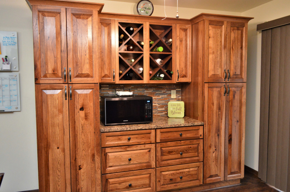 Exempel på ett stort rustikt brun brunt kök, med en undermonterad diskho, luckor med upphöjd panel, skåp i mellenmörkt trä, bänkskiva i kvartsit, flerfärgad stänkskydd, stänkskydd i stickkakel, svarta vitvaror, laminatgolv, en köksö och brunt golv