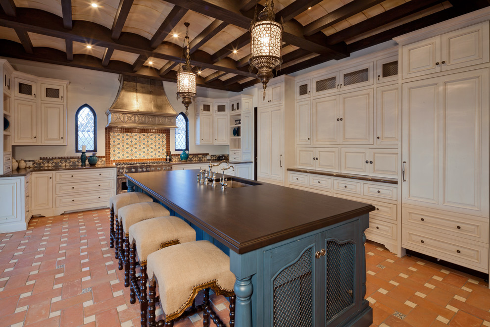 Foto på ett medelhavsstil kök, med luckor med upphöjd panel, vita skåp, träbänkskiva, flerfärgad stänkskydd och integrerade vitvaror