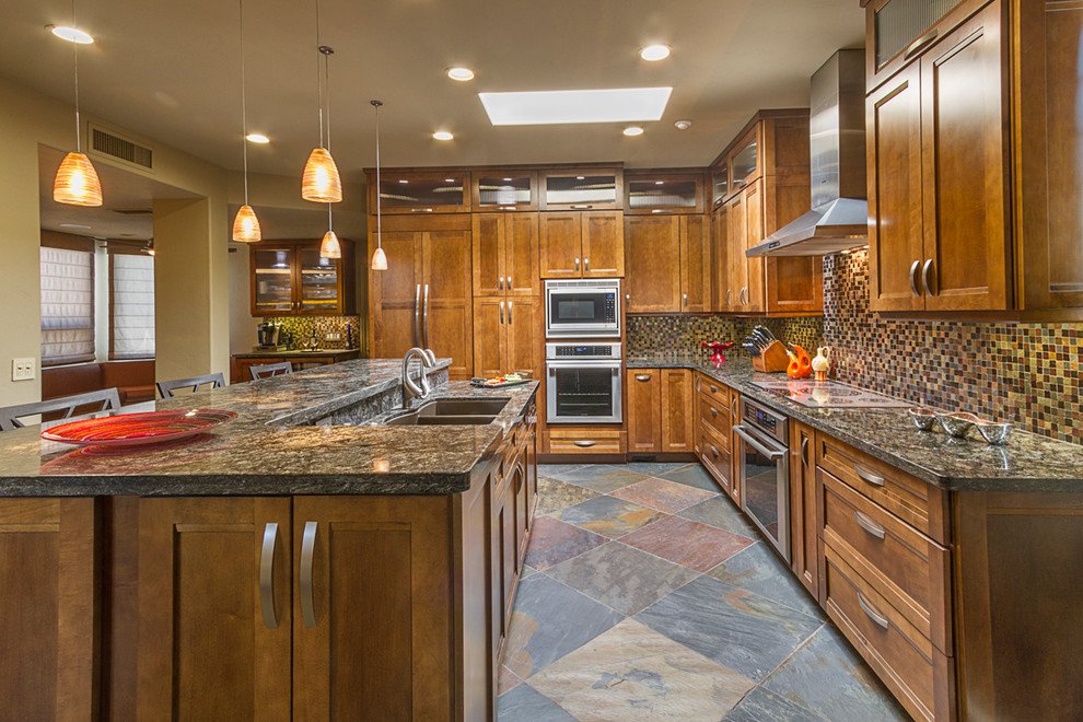 Foto de cocina clásica renovada de tamaño medio con fregadero bajoencimera, armarios con paneles empotrados, puertas de armario de madera oscura, encimera de granito, salpicadero multicolor, salpicadero con mosaicos de azulejos, electrodomésticos de acero inoxidable, suelo de pizarra y una isla