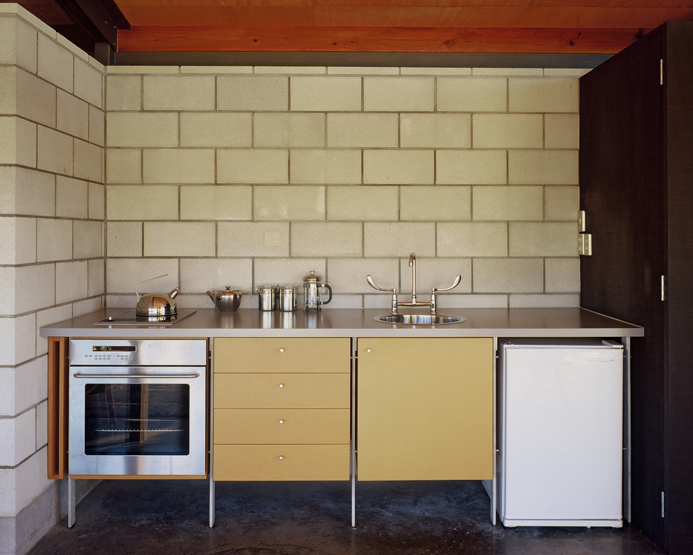 Foto di una piccola cucina contemporanea con lavello a vasca singola, paraspruzzi grigio, elettrodomestici in acciaio inossidabile, pavimento in cemento e nessuna isola