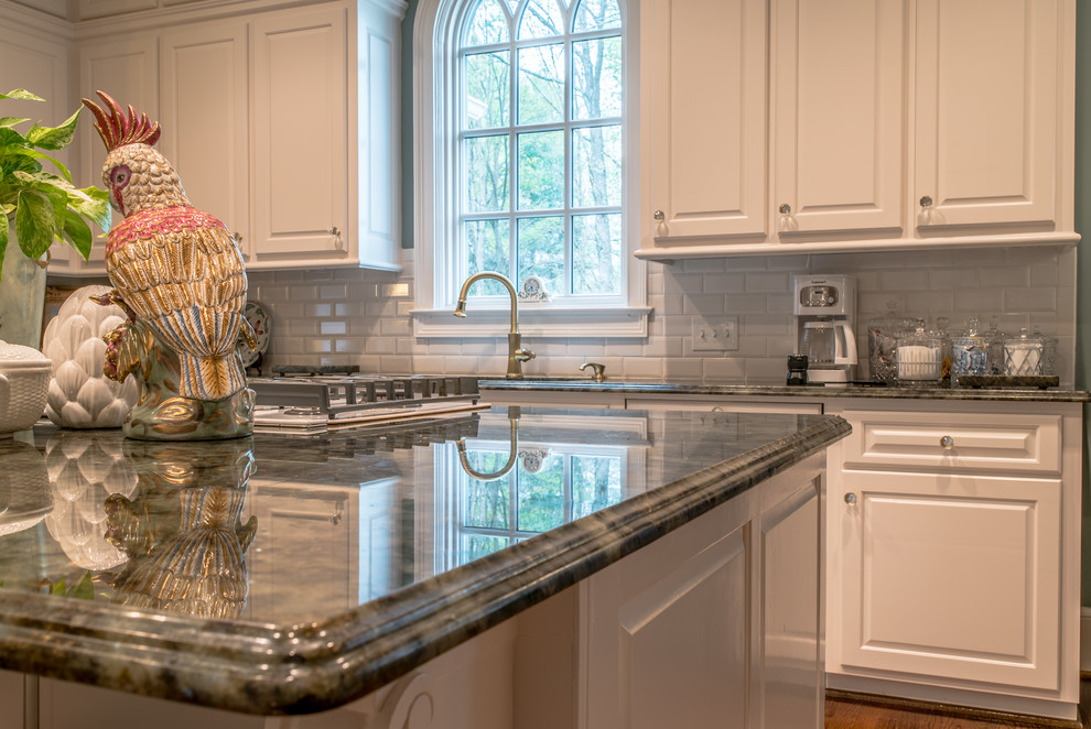 Example of a huge classic galley light wood floor open concept kitchen design in Charleston with a double-bowl sink, raised-panel cabinets, white cabinets, quartzite countertops, white backsplash, subway tile backsplash, white appliances and an island