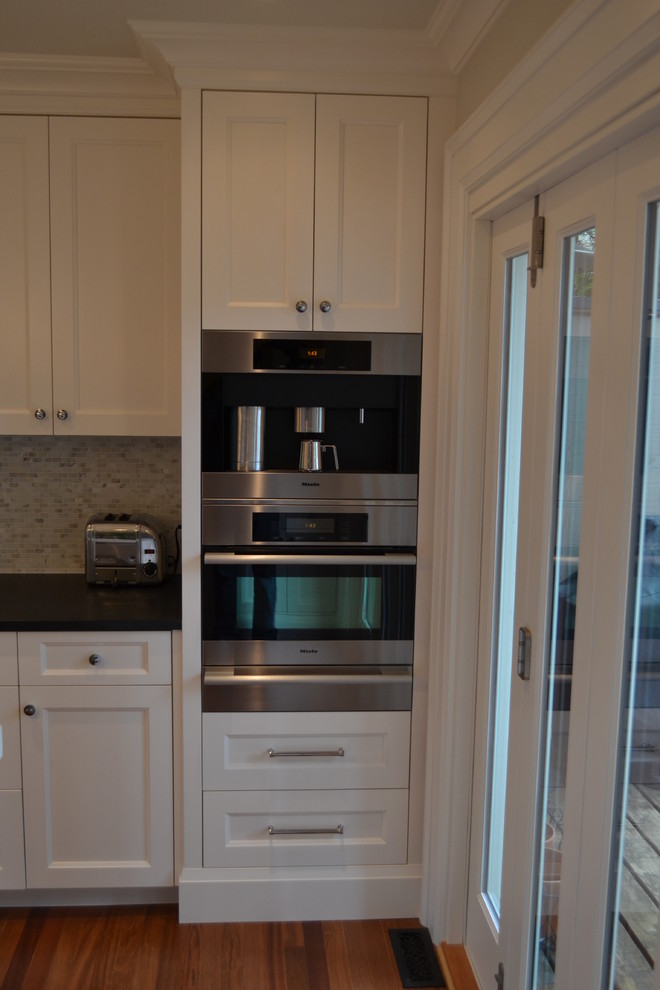 Modelo de cocinas en U tradicional cerrado con armarios estilo shaker, puertas de armario blancas y electrodomésticos de acero inoxidable