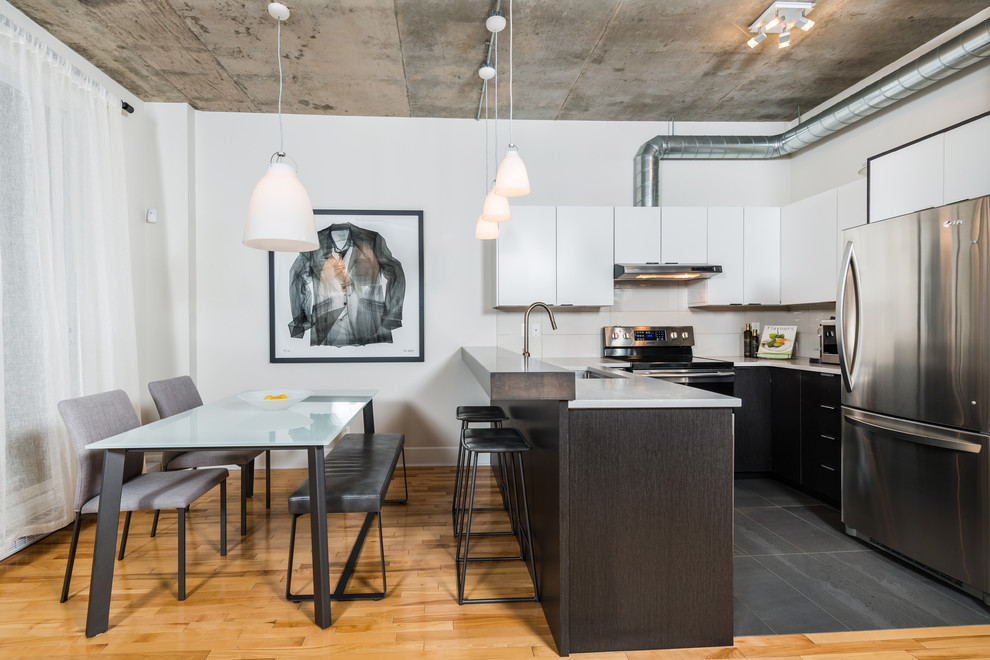 Urban u-shaped light wood floor eat-in kitchen photo in Montreal with an undermount sink, flat-panel cabinets, white cabinets, beige backsplash, stainless steel appliances and a peninsula